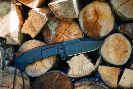 Foto de Folding heavy expedition knife and firewood in nature, close-up photo. High quality photo - Imagen libre de derechos