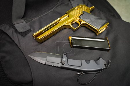 Téléchargez les photos : Firearms and bladed weapons. Gold Desert Eagle pistol and folding tactical knife. High quality photo - en image libre de droit