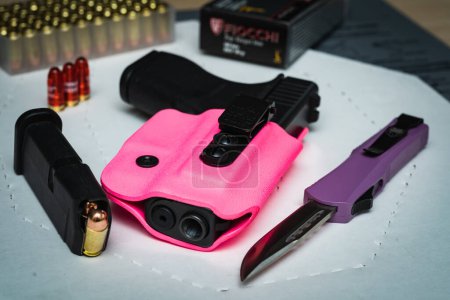 Photo for Baltic States, October 24, 2023. Glamorous weapons for the ladies, a Glock 42 pistol with a pink holster and folding knife with a bright purple handle. High quality photo - Royalty Free Image