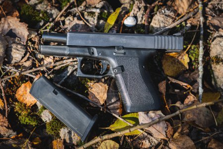 A pistol with a slide stop lies on the ground on autumn leaves. High quality photo