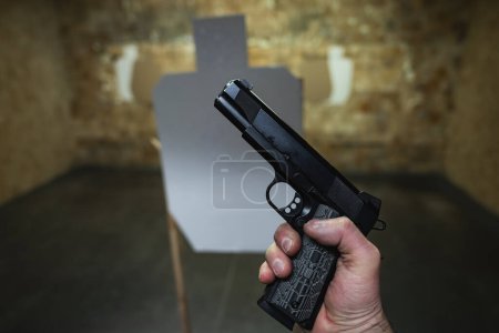 Foto de Pistola M1911 en la mano de un hombre en un campo de tiro. Foto de alta calidad - Imagen libre de derechos