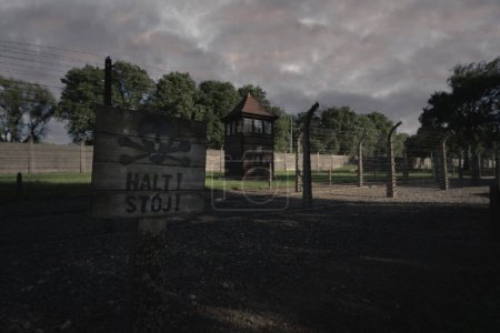 Auschwitz extermination camp in Poland, a fence with barbed wire and a sign saying stand in local and German. High quality photo