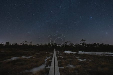 Night scene, landscape astrophoto at Seli swamp, wooden path for travelers on foot and starry sky. 