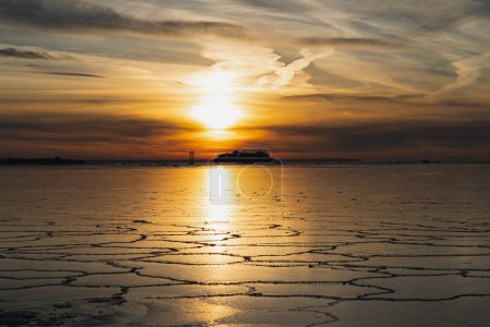 Seascape in winter at sunset. View from the shore of Viimsi, a ferry sailing on the frozen sea. High quality photo