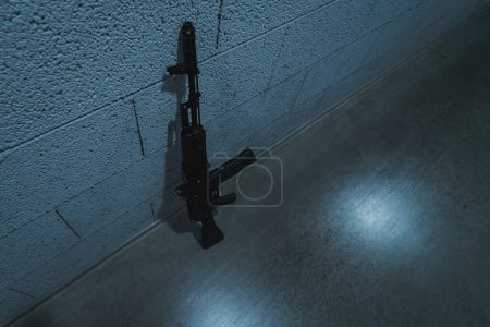 Téléchargez les photos : Ak 74m fusil près du mur dans une pièce avec un mauvais éclairage. Photo de haute qualité - en image libre de droit