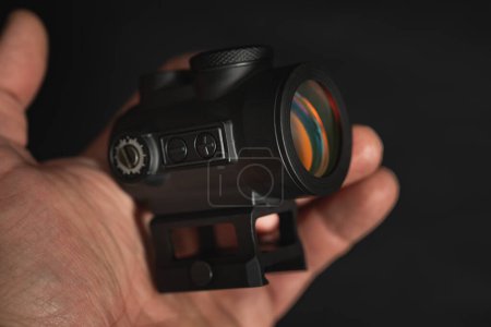 Photo for A modern red dot sight in a mans hand, close-up photo. High quality photo. - Royalty Free Image