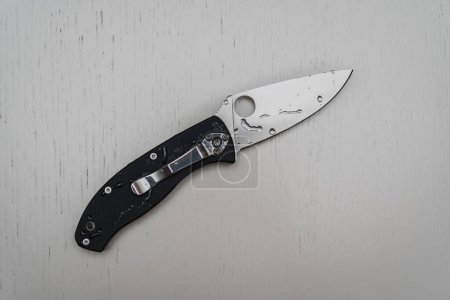 Beautiful pocket folding knife on a wooden white background. High quality photo