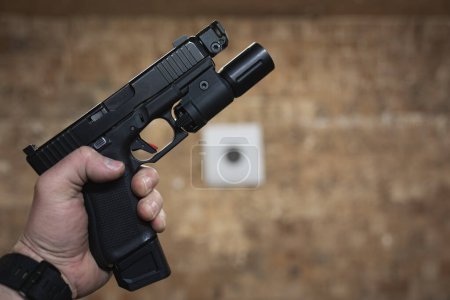 Tactical pistol with a flashlight in a man's hand at a shooting range. High quality photo