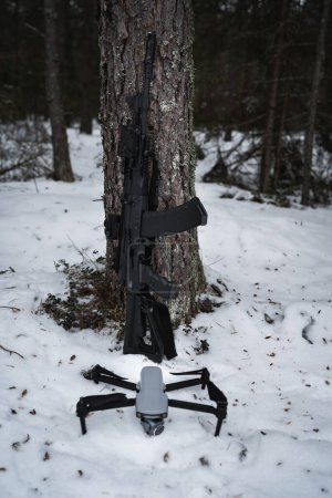 AK 12 rifle near a tree in the forest and a drone with a camera, horizontal photo. High quality photo