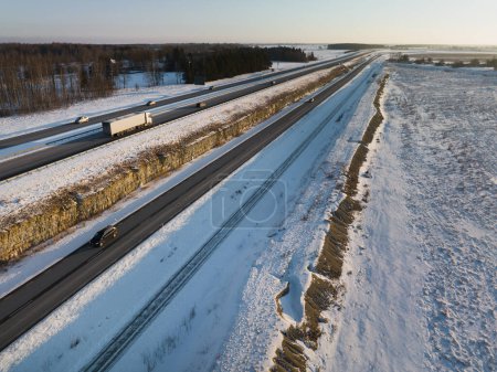 Ein LKW und andere Fahrzeuge fressen an einem Wintermorgen entlang der Autobahn, Foto von einer Drohne. Hochwertiges Foto
