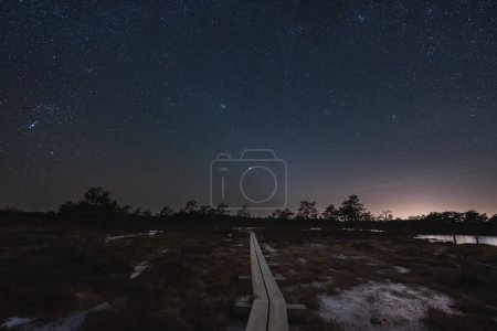 Night scene, landscape astrophoto at Seli raba, wooden path for travelers and starry sky. 
