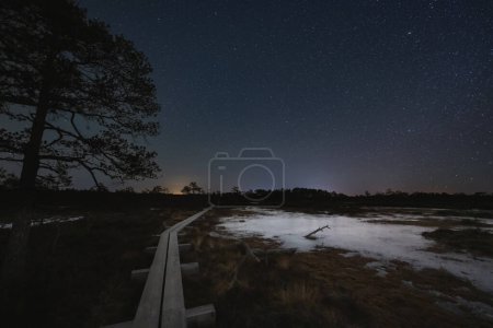 Night scene, landscape astrophoto at Seli raba, wooden path for travelers on foot and starry sky. 