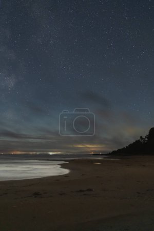 Night landscape with a starry sky, sandy shore of Lake Peipus. Vertical photo. 