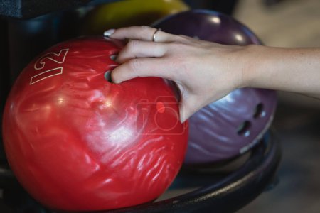Foto de La mano de una mujer toma una bola roja de bolos, foto de cerca. - Imagen libre de derechos