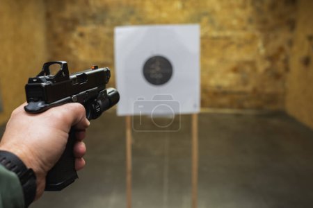 Pistola táctica disparando a un objetivo en un campo de tiro, foto en primera persona. 