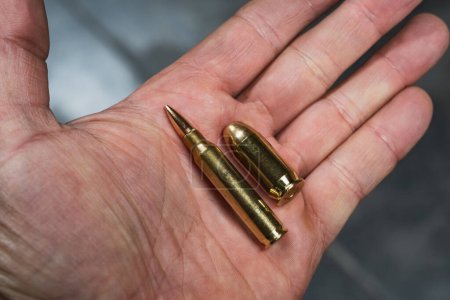 Rifle and pistol cartridge in a man's hand close-up. 