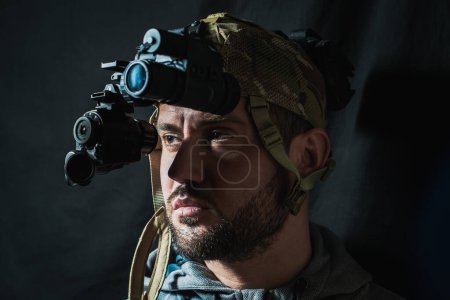 Portrait of a military man with a beard with a binocular night vision device on his head. 
