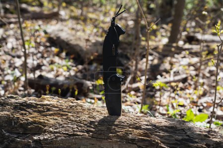 A large folding knife is stuck into a fallen dead tree. Close up. 