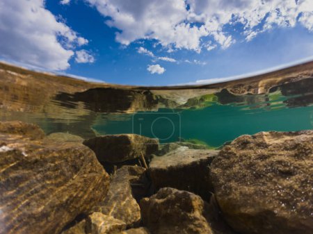 Action camera underwater photography at the Rummu quarry, clear water, rocky bottom and cloudy sky. 