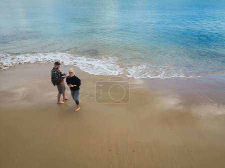 Un pilote de drone homme avec sa femme sur une plage de sable en vacances, vue de la photo d'en haut. 