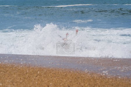 Ein junges Paar spaziert an einem Frühlingstag am Strand von Nazar während der Wellen, Foto von einer Drohne.