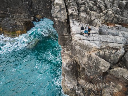 A couple stands on a steep shore near the ocean. Boca do Inferno (Devil's Mouth) in Cascais is a huge grotto in the coastal cliffs of Portugal. Couple 
