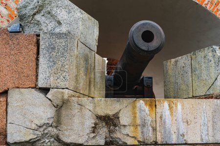 An old artillery cannon in a fortress with traces of cannonballs hitting the wall. 