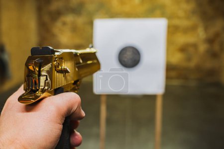 Shooting from a gold-colored Desert Eagle pistol in a shooting range at a paper target, first-person view. 