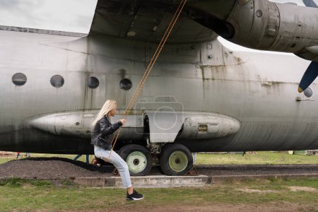A girl swings on a swing mounted on an old military cargo plane. 