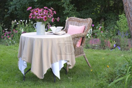Foto de Ramo de equinácea purpurea en un jarrón sobre la mesa. Un lugar para relajarse y leer en el jardín - Imagen libre de derechos