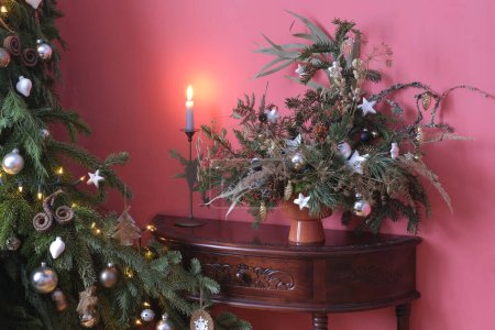 Weihnachtskomposition aus lebenden Materialien, verziert mit gläsernem Weihnachtsbaumspielzeug, Sternen aus Paraffin und Messingglocken auf einer Konsole aus Holz