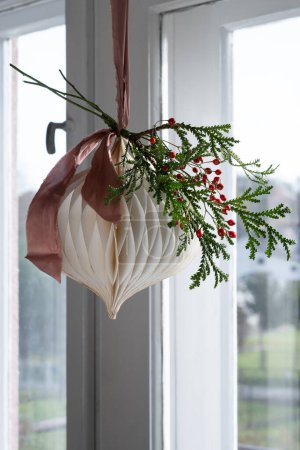 Téléchargez les photos : Décorations suspendues en papier pour Noël sur le fond de la fenêtre - en image libre de droit