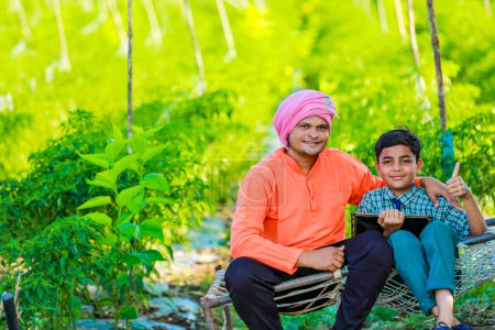 Foto de Lindo niño agricultor indio en uniforme escolar con su padre en el campo de la agricultura, feliz padre e hijo - Imagen libre de derechos