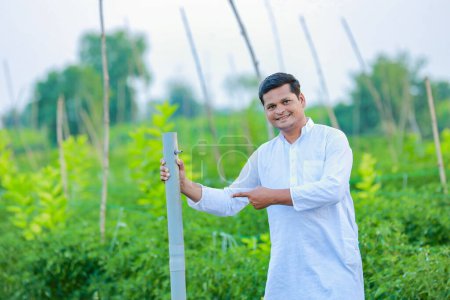 Foto de Granjero indio feliz, sosteniendo la tubería en la mano y mirando cámara - Imagen libre de derechos