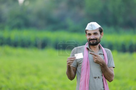 Foto de Agricultor indio con tarjeta de cajero automático en las manos, agricultor indio feliz, árbol de guisantes - Imagen libre de derechos