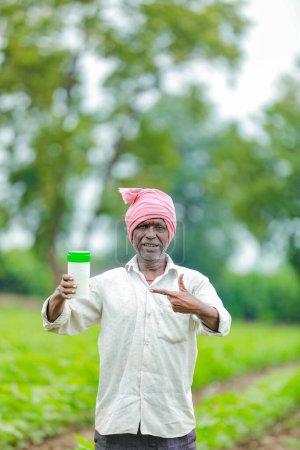 Photo for Indian happy farmer holding empty Bottle in hands, happy farmer showing white Bottle - Royalty Free Image