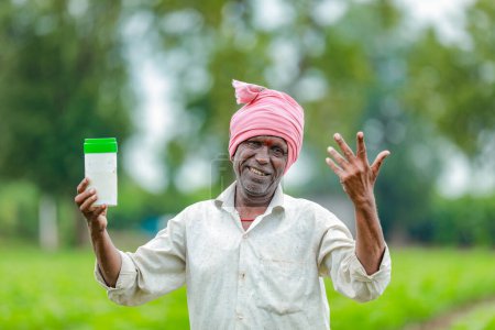 Photo for Indian happy farmer holding empty Bottle in hands, happy farmer showing white Bottle - Royalty Free Image