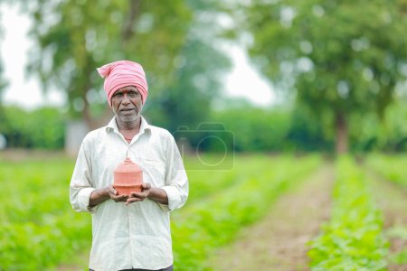 Foto de Granjero indio sosteniendo gullak en la mano, concepto de ahorro, granjero pobre feliz - Imagen libre de derechos