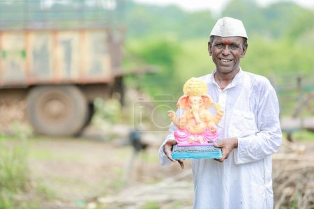 Foto de Viejo indio sosteniendo al Señor Ganesha ídolo en las manos, feliz viejo pobre hombre - Imagen libre de derechos