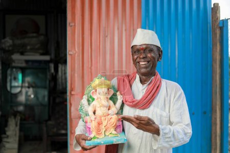 Téléchargez les photos : Vieux indien tenant Lord Ganesha idole dans les mains, heureux vieil homme pauvre - en image libre de droit