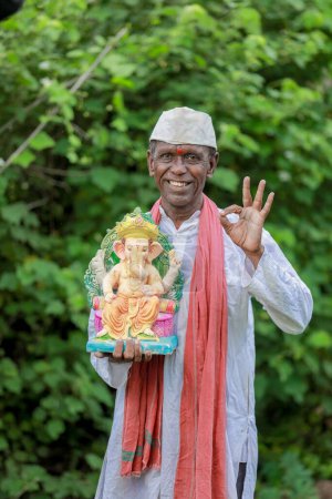 Foto de Viejo indio sosteniendo al Señor Ganesha ídolo en las manos, feliz viejo pobre hombre - Imagen libre de derechos