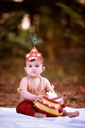 Téléchargez les photos : Heureux Janmashtami, petit garçon indien se faisant passer pour Shri Krishna ou kanha ou kanhaiya avec Dahi Handi photo - en image libre de droit