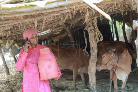 Glücklicher indischer Bauer, der Milch im Bauernhof verkauft - Konzept der Milchproduktion agri business, ländliches Indien, Wachstum und Landwirtschaft