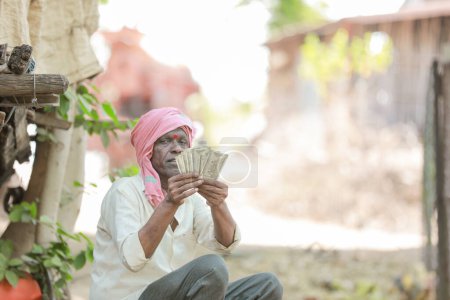Téléchargez les photos : Rural Farmer Man Standing Field Affichage de billets en monnaie indienne - en image libre de droit