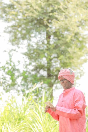 Téléchargez les photos : Agriculteur indien tenant roupie dans les mains - en image libre de droit