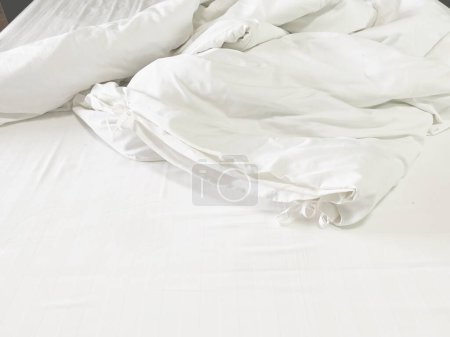 Unmade bed; wrinkled pillowcases, bed sheet and duvet.
