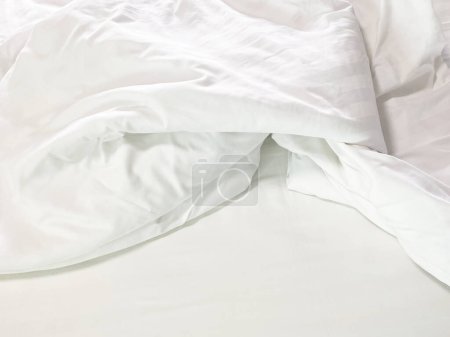 Ungeschminktes Bett; faltige Kissenbezüge, Bettlaken und Bettdecken.