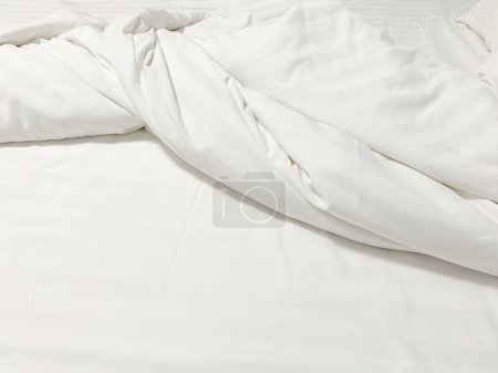 Ungeschminktes Bett; faltige Kissenbezüge, Bettwäsche und Duve.