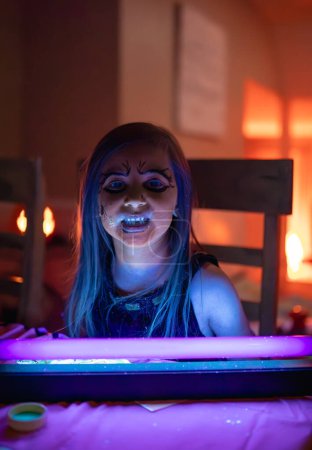 Photo for Young Girl with Face Paint Glowing Under Blacklight - Enchating Halloween Glow - Royalty Free Image