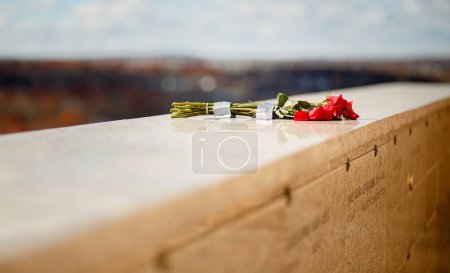 Foto de Ramo de rosas rojas colocadas en la pared de piedra de mármol en la tumba conmemorativa del mausoleo - Imagen libre de derechos